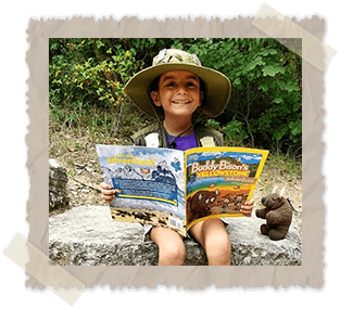 Little girl sitting outside on a rock reading Buddy Bison's Yellowstone Adventure