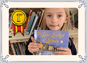 Little girl holding The Lost Locket of Lewes book with first place award