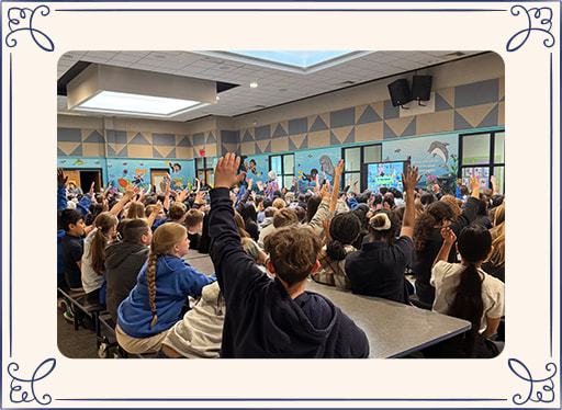 Children raising hands during a presentation with Ilona Holland